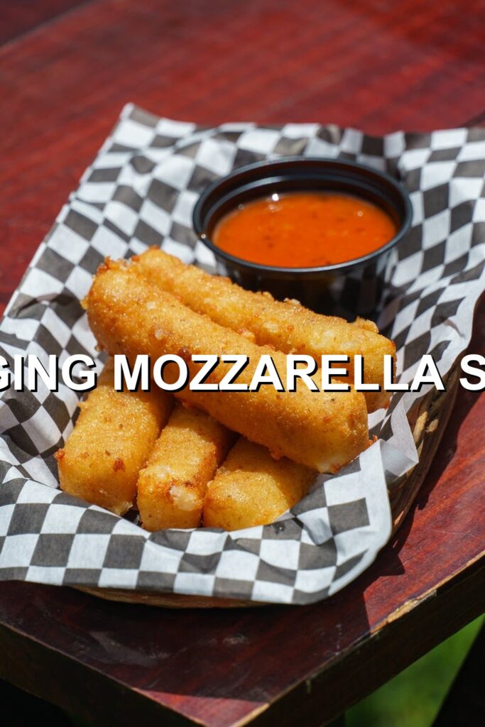 Crispy mozzarella sticks, golden and bubbly, served with a side of vibrant red sauce.